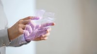 Person holding transparent digital interface with purple holographic elements and glowing data visualization for technology, innovation, and futuristic business concepts.