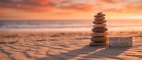 Balanced stone cairn on sandy beach at golden sunset with inner balance wellness sign for meditation and mindfulness practices.