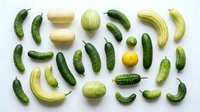 Fresh green cucumbers and pickles arranged on white background for healthy eating and food preparation concepts.