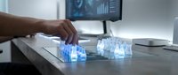 Professional scientist conducting laboratory research with illuminated test tubes and digital analysis on computer monitor in modern medical facility.