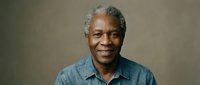 Smiling mature African American man in denim shirt against neutral background, expressing warmth and confidence for lifestyle and business content.
