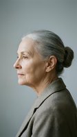 Senior woman with gray hair in bun, wearing taupe blazer, profile portrait against neutral background. Suitable for healthcare, aging, lifestyle, and professional business concepts.