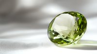 Sparkling green peridot gemstone with oval cut on white surface casting soft shadows, luxury jewelry element for designers and jewelers.