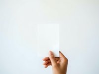 Hand holding blank white card against neutral background, suitable for business messaging, promotional campaigns, and marketing materials.