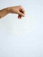 Female hand with medium skin tone holding an invisible string or thread against white background, symbolizing control, manipulation, or puppet concept for business and psychology themes.