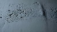 Close-up of fine gray powder or dust particles scattered across a smooth surface, suitable for industrial, construction, or material texture backgrounds.