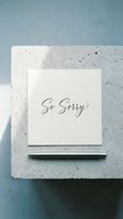So Sorry greeting card with elegant script lettering on concrete surface with pen, minimal sympathy note concept.