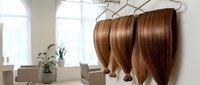 Professional hair extensions hanging on display in modern salon interior with natural lighting and clean aesthetic for beauty industry marketing.
