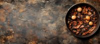 Rustic cast iron pan with mushrooms and bacon on dark textured background with copy space, top view. Food photography in moody lighting style.