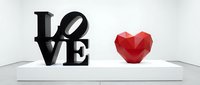 Black LOVE sculpture and red geometric heart on white pedestal in modern gallery, symbolizing romance and contemporary art installation.