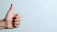 Hand showing thumbs up gesture on clean white background expressing approval and positive feedback for business presentations.