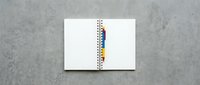 Open spiral notebook with colorful page dividers on concrete surface for office organization and planning projects.