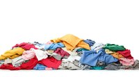 Colorful pile of wrinkled casual clothes, t-shirts, and garments scattered in messy heap on white background, isolated laundry concept for cleaning service.