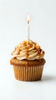 Spiced cupcake with caramel drizzle, cream frosting, and lit birthday candle on white background for celebration and party designs.