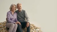 Happy senior Caucasian couple sitting together surrounded by golden coins symbolizing retirement savings and financial security planning.