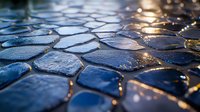 Wet cobblestone pavement with sunlight reflection creating golden highlights on blue stones. Ancient European street detail with water drops after rain.