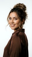 Young Hispanic woman with messy bun hairstyle smiling warmly in brown hoodie against white background for lifestyle and fashion content.