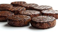 Grilled beef patties with charred grill marks and juicy texture on white background, close-up view showing caramelized surface and meat preparation technique.
