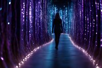 Silhouette of woman walking through magical illuminated tunnel with purple and blue lights creating dreamy atmosphere. Glowing path leads into mysterious distance.