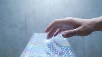 Hand touching futuristic holographic keyboard interface with glowing keys and digital elements for technology and innovation concepts.