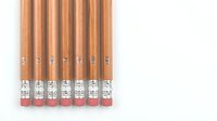 Row of wooden pencils with pink erasers arranged in line on white background isolated for educational and office design projects.