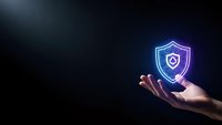 Hand holding glowing cybersecurity shield icon with protection symbol on dark background for digital security and data protection concepts.