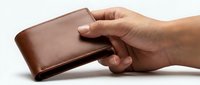 Hand holding brown leather wallet on white background, perfect for financial services, banking, shopping and payment concepts.
