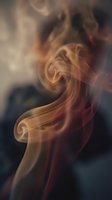 Swirling colorful smoke in warm golden and red tones against a dark background, creating an abstract, mysterious atmosphere.