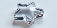 Clear glass star-shaped bowl or dish with smooth curved edges and reflective surface, perfect for serving snacks or decorative display on white background.
