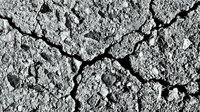 Cracked dry earth surface showing deep fissures and drought conditions in barren landscape. Natural disaster and climate change environmental concept.
