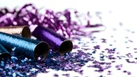 Festive party poppers with scattered purple and blue metallic confetti on white surface, creating celebratory atmosphere for holiday and event decorations.