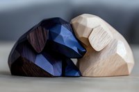Minimalist wooden sculpture showing two abstract geometric shapes in contrasting dark blue and natural wood tones embracing in artistic harmony.