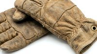 Worn leather work gloves with quilted insulation and reinforced palms, isolated on white background for design, construction, gardening, and labor industry use.