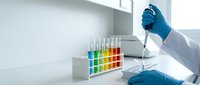 Laboratory scientist in blue gloves conducting chemical analysis with colorful test tubes in modern research facility for scientific experiments.