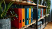 Colorful office binders arranged on wooden shelf with potted plant, creating organized workspace atmosphere. Modern business storage solution for documents.