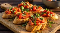 Toasted bread slices topped with diced tomatoes, fresh herbs, and olive oil on wooden serving board for appetizers, bruschetta recipes, and Italian cuisine content.