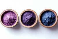 Vibrant mineral pigment powders in pink, purple and blue shades presented in wooden bowls on white background, natural cosmetic ingredients for makeup and art supplies.
