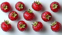 Fresh ripe red raspberries with green leaves arranged in rows on white background, top view close up macro shot of organic berries for food design.