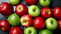 Fresh red and green apples with water drops on dark background, top view. Organic fruits pattern for healthy eating and natural food concept.