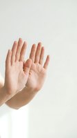 Two open hands raised up showing palms in stop gesture or surrender pose against neutral background for communication and body language concepts.