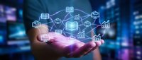 Businessman holding glowing digital icons representing education, knowledge sharing, and business growth in connected network on blurred city background.