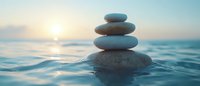 Balanced zen stones stacked on water surface at sunset, symbolizing harmony, meditation, and tranquility for wellness and spa concepts.