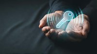 Businessman holding glowing digital key icon with security lines, representing cybersecurity, data protection, and access control solutions for technology and business.