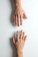 Two male hands with wedding rings reaching toward each other on white background symbolizing connection, partnership and human touch.