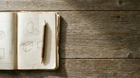 Overhead view of open sketchbook with geometric drawings and pencil on rustic wooden surface, suitable for design, education, and creative projects.