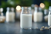 Fresh milk in glass bottle on dark background with bokeh lights and scattered nuts, dairy product photography for food packaging and advertising.
