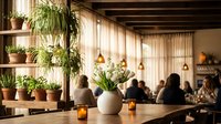 Cozy restaurant interior with wooden shelves displaying potted plants and ceramic vases, warm lighting creating inviting dining atmosphere for customers.