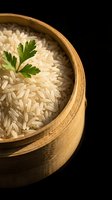 Cooked white rice in wooden bowl garnished with fresh parsley on black background for culinary and food photography projects.