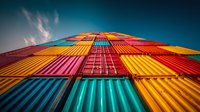Colorful shipping containers stacked high against blue sky creating vibrant geometric pattern for logistics and transportation industry concepts.
