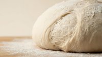 Uncooked croissant dough with laminated layers dusted with flour, ready for baking in bakery or culinary applications.